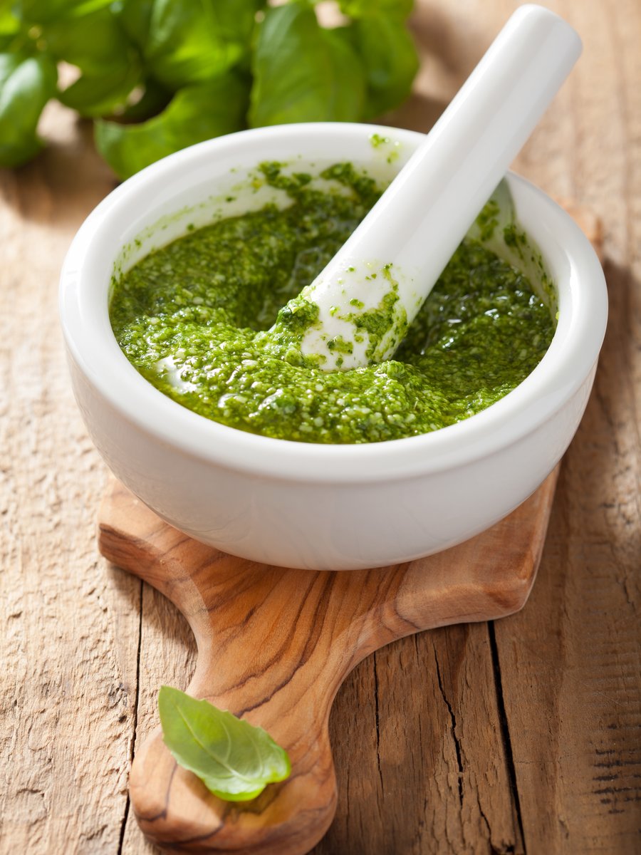 Pesto dans un mortier avec son pilon sur planche en bois