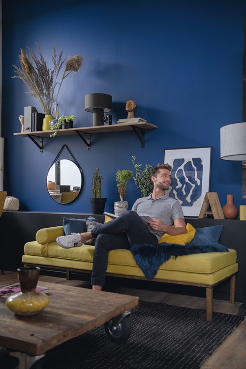 Un homme assis sur un canapé dans une pièce avec un mur bleu